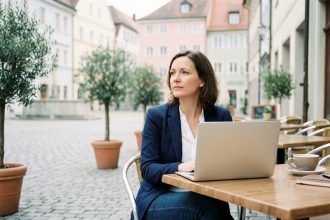 Femme en blazer assise au cafe regardant la place